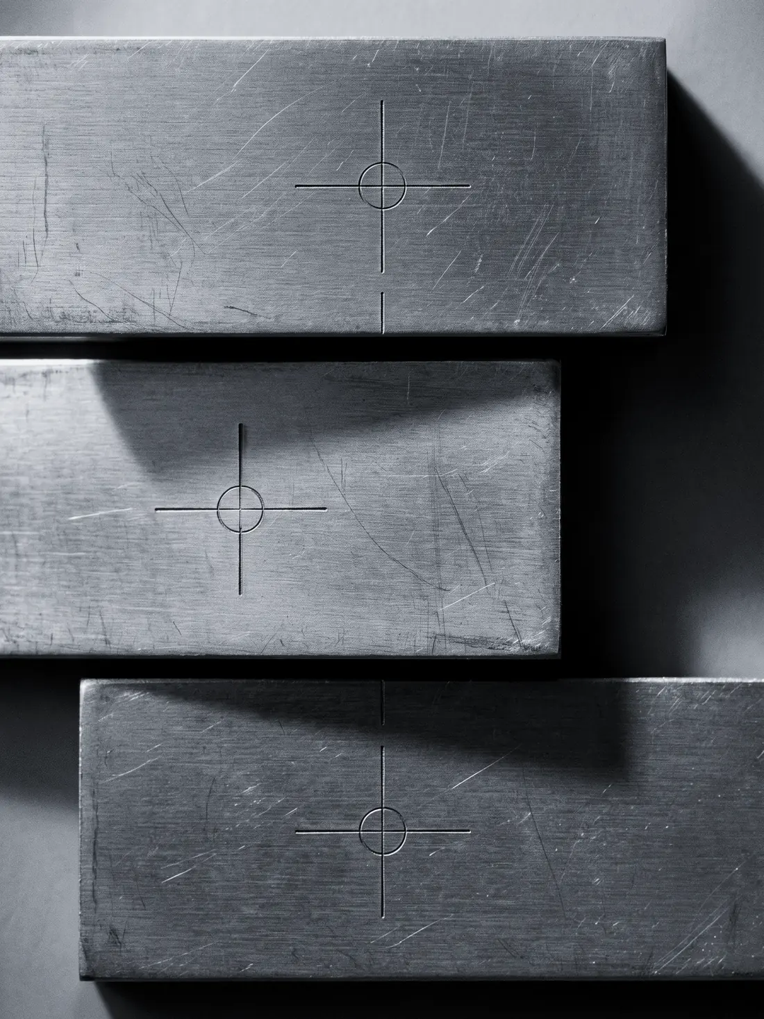 Three steel plates lit from one side, each cut with a fine crosshair target,
        the middle plate shifted so its target no longer lines up.